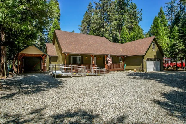 a view of a house with a yard and large tree