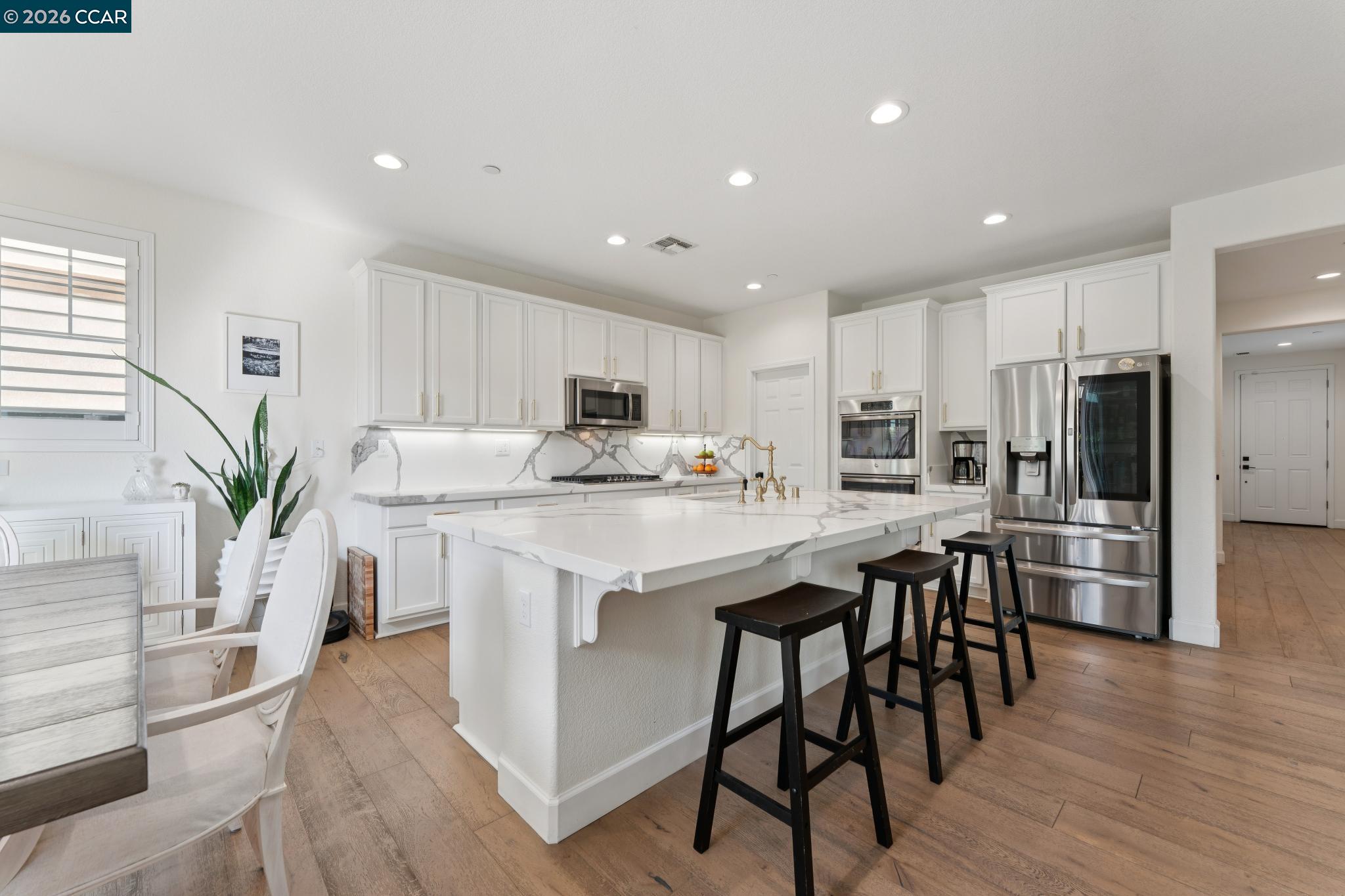 1226 Sierra Trail Road Oakley, CA 94561 - Photo 11 of 60 a kitchen with stainless steel appliances kitchen island granite countertop a table chairs refrigerator a sink and white cabinets