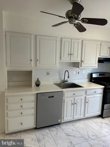a kitchen with a sink dishwasher and white cabinets