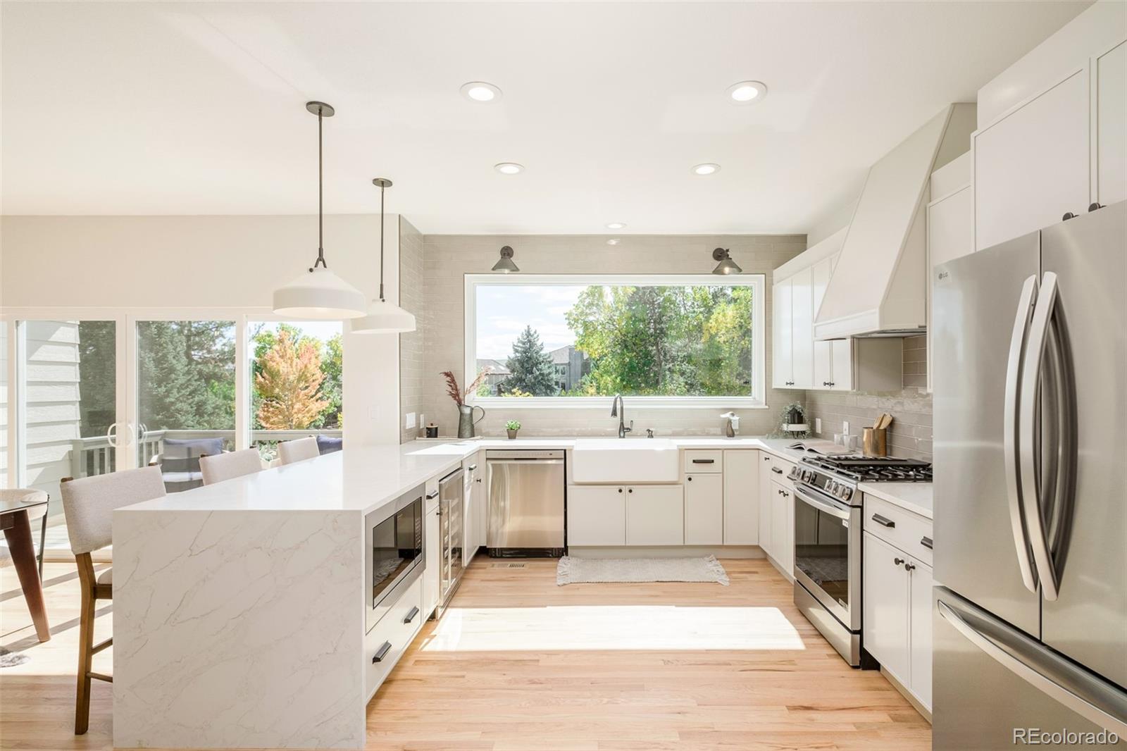 8176 Lone Oak Court Lone Tree, CO 80124 - Photo 10 of 50 a large kitchen with kitchen island a large counter top space a sink stainless steel appliances and windows