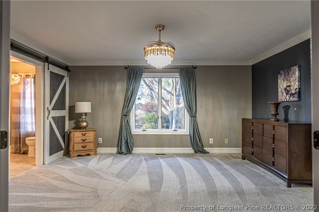 1075 Burning Tree Road Pinehurst, NC 28374 - Photo 11 of 25 a bedroom with a bed and a chandelier