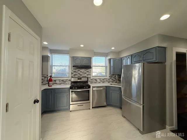 a kitchen with stainless steel appliances kitchen island granite countertop a refrigerator and a stove