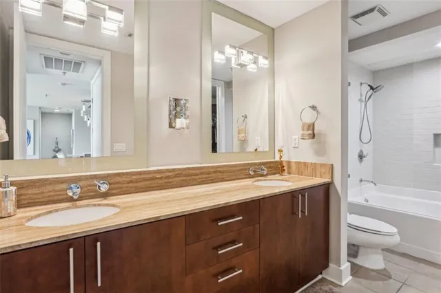 a bathroom with a granite countertop sink toilet a large mirror a shower and a bathtub
