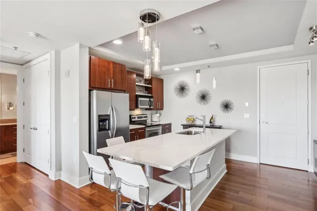 a kitchen with stainless steel appliances a kitchen island hardwood floor and a sink
