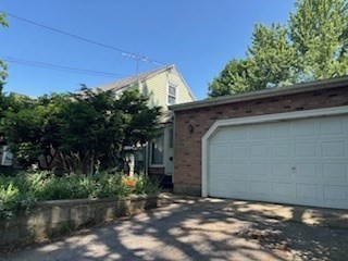 a backyard of a house with plants and large tree