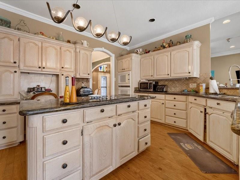 1704 South Bowen Road Pantego, TX 76013 - Photo 10 of 26 a kitchen with granite countertop white cabinets white stainless steel appliances and wooden floors