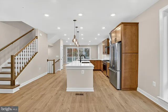 a living room with stainless steel appliances furniture wooden floor and a view of kitchen