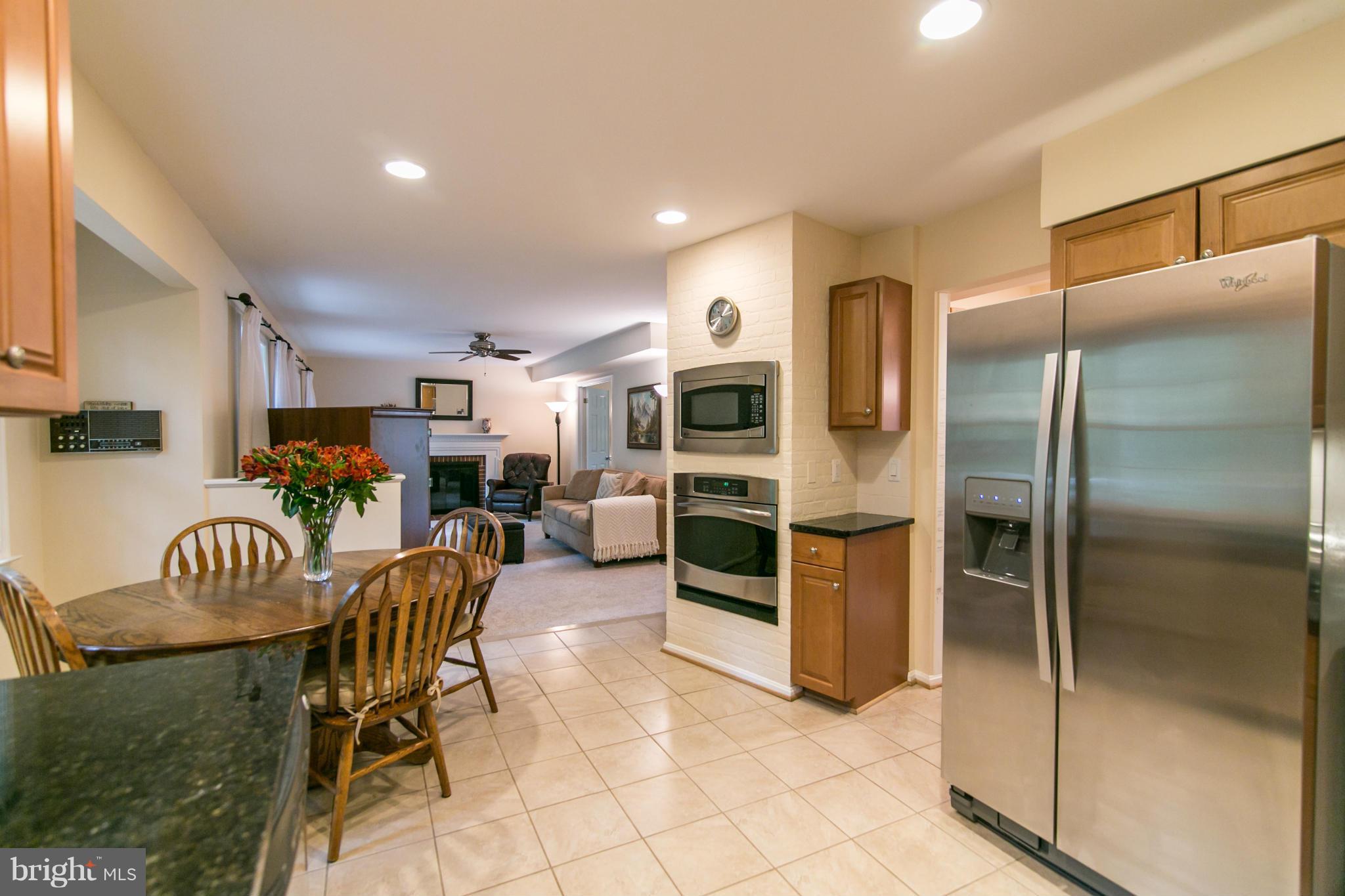 10819 Cross School Road Reston, VA 20191 - Photo 8 of 30 a kitchen with stainless steel appliances kitchen island granite countertop a refrigerator oven a sink a dining table and chairs
