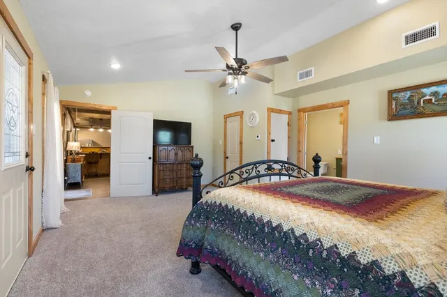 a bedroom with a large bed a flat tv screen and a chandelier