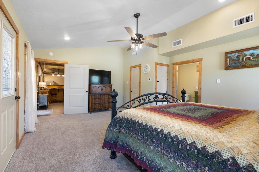 25525 Ranch Road 2323 Llano, TX 78643 - Photo 21 of 40 a bedroom with a large bed a flat tv screen and a chandelier