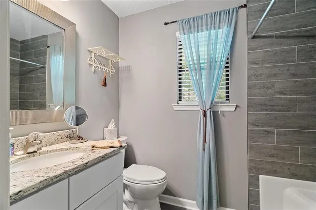 a bathroom with a granite countertop sink a toilet and shower