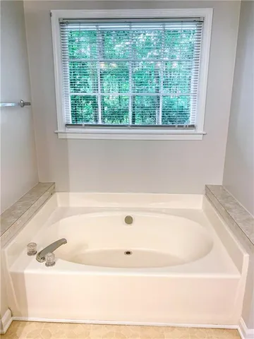 a white bath tub sitting in a bathroom next to a window