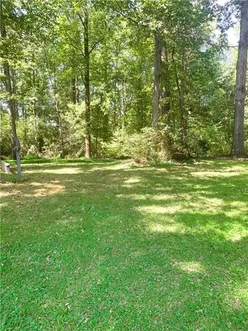 a big yard with lots of green space and trees in the background
