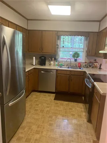 a kitchen with stainless steel appliances granite countertop a refrigerator a sink a stove top oven and a refrigerator