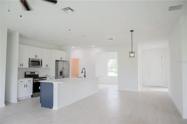 a view of a kitchen with a sink a kitchen island a stove a microwave and cabinets