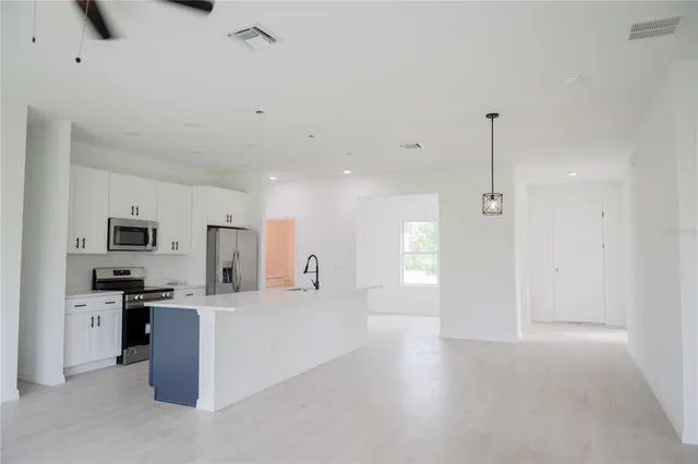 a view of a kitchen with a sink a kitchen island a stove a microwave and cabinets
