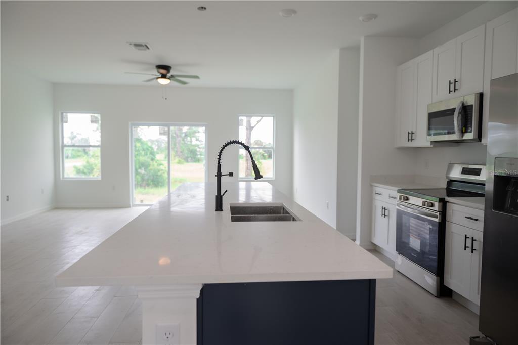 46 Master Drive Placida, FL 33946 - Photo 34 of 44 a view of a kitchen with a sink a kitchen island a stove a microwave and cabinets