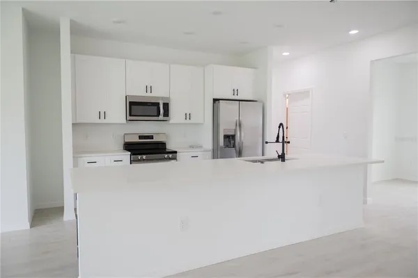 a kitchen with stainless steel appliances granite countertop a refrigerator a stove and a microwave