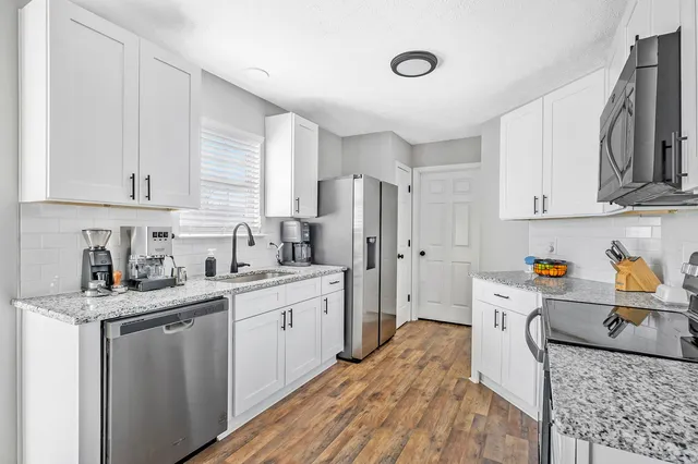 a kitchen with stainless steel appliances granite countertop a sink stove and refrigerator