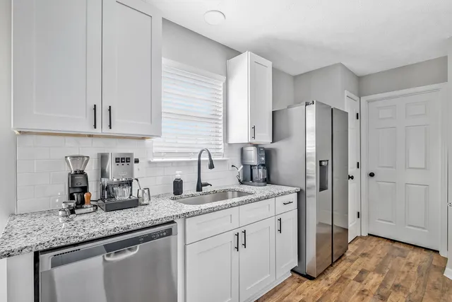 a kitchen with stainless steel appliances granite countertop a sink refrigerator and cabinets