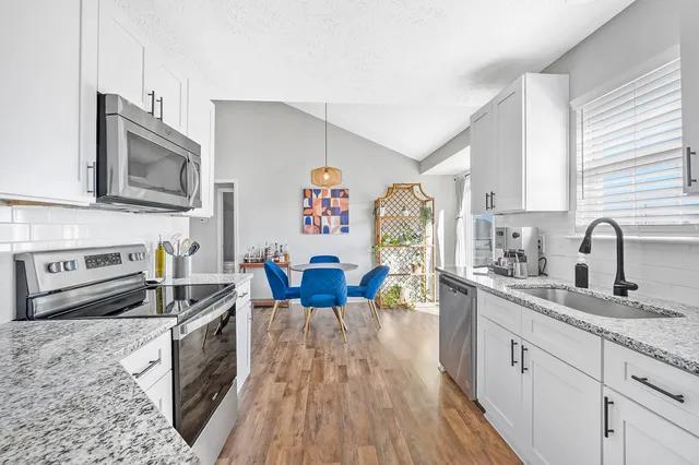 a kitchen with stainless steel appliances granite countertop a stove a sink dishwasher and a microwave oven with wooden floor