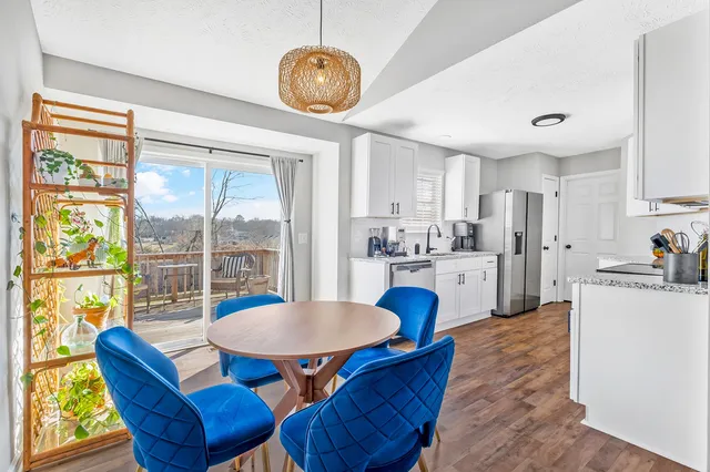 a kitchen with stainless steel appliances granite countertop a stove a refrigerator a kitchen island a dining table and chairs with wooden floor