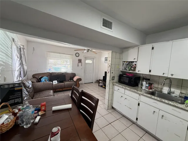 a kitchen with stainless steel appliances kitchen island granite countertop a refrigerator a stove a sink dishwasher and a dining table with wooden floor