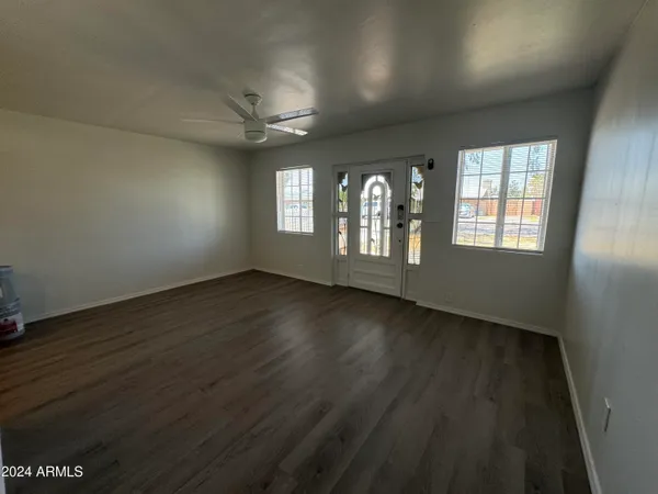 an empty room with wooden floor and windows