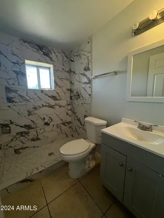 a bathroom with a granite countertop toilet a sink and a mirror