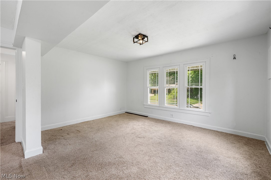 371 Merriman Road Akron, OH 44303 - Photo 15 of 27 Spacious room featuring three large windows, a neutral carpet, a contemporary flush-mount ceiling light fixture, and freshly painted white walls and trim