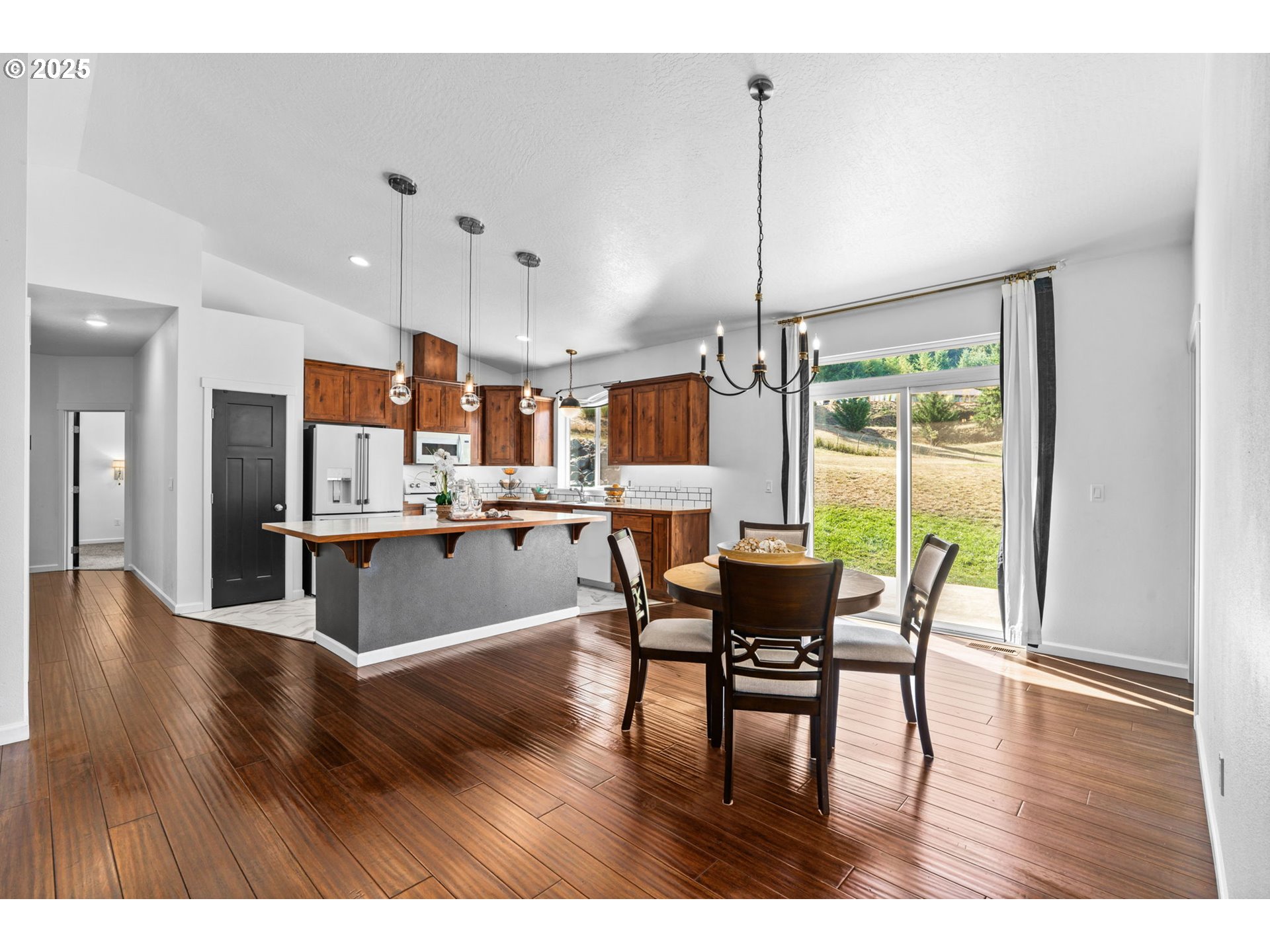2187 East Madison Avenue Cottage Grove, OR 97424 - Photo 7 of 41 a open kitchen with stainless steel appliances granite countertop a refrigerator a microwave a stove and a dining table with wooden floor