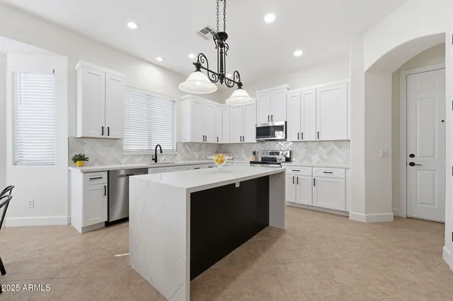 a kitchen with kitchen island white cabinets and stainless steel appliances