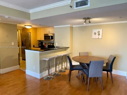 a kitchen with stainless steel appliances a dining table chairs and a wooden floor