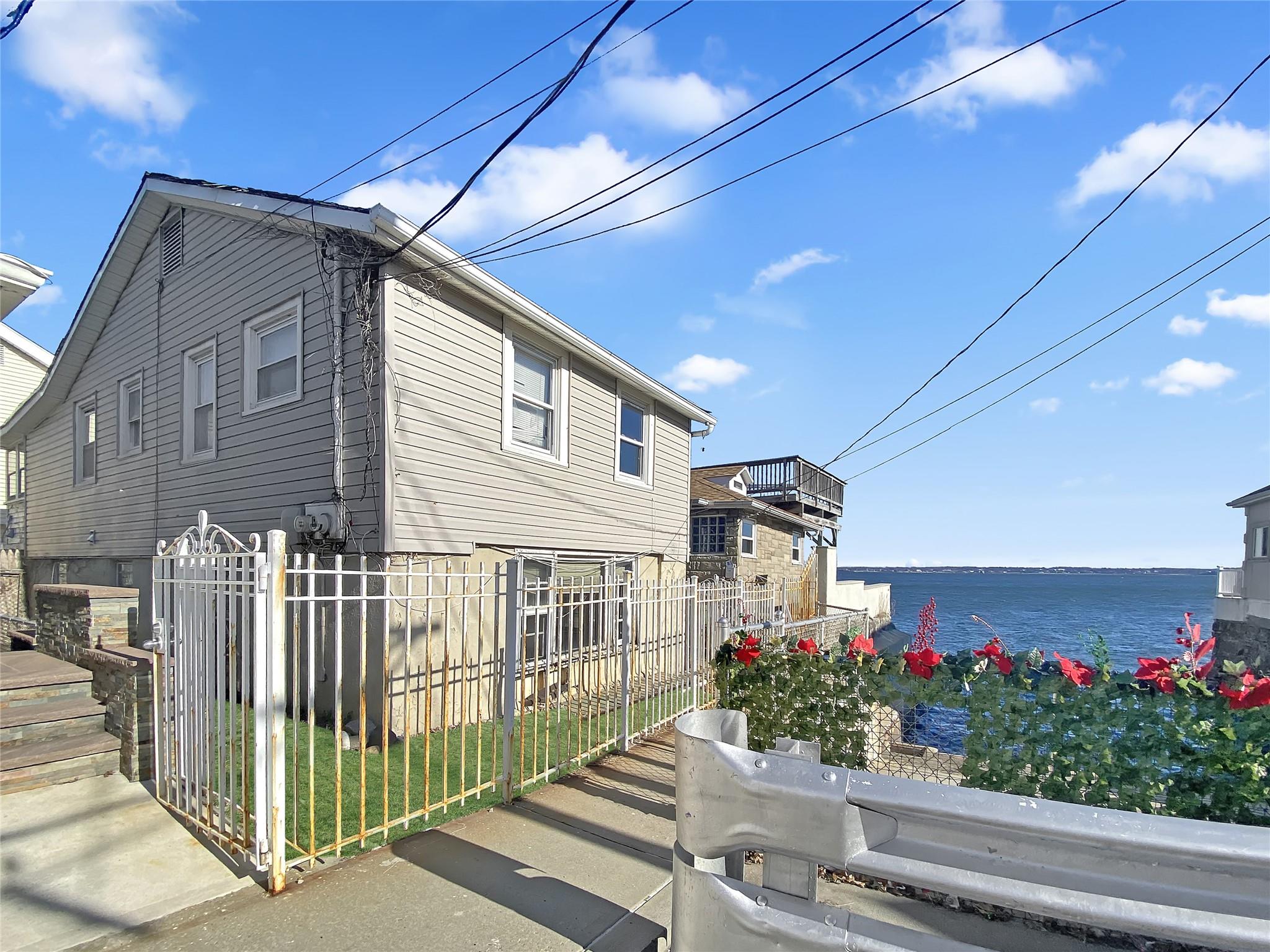 View of home's exterior with a water view and fence