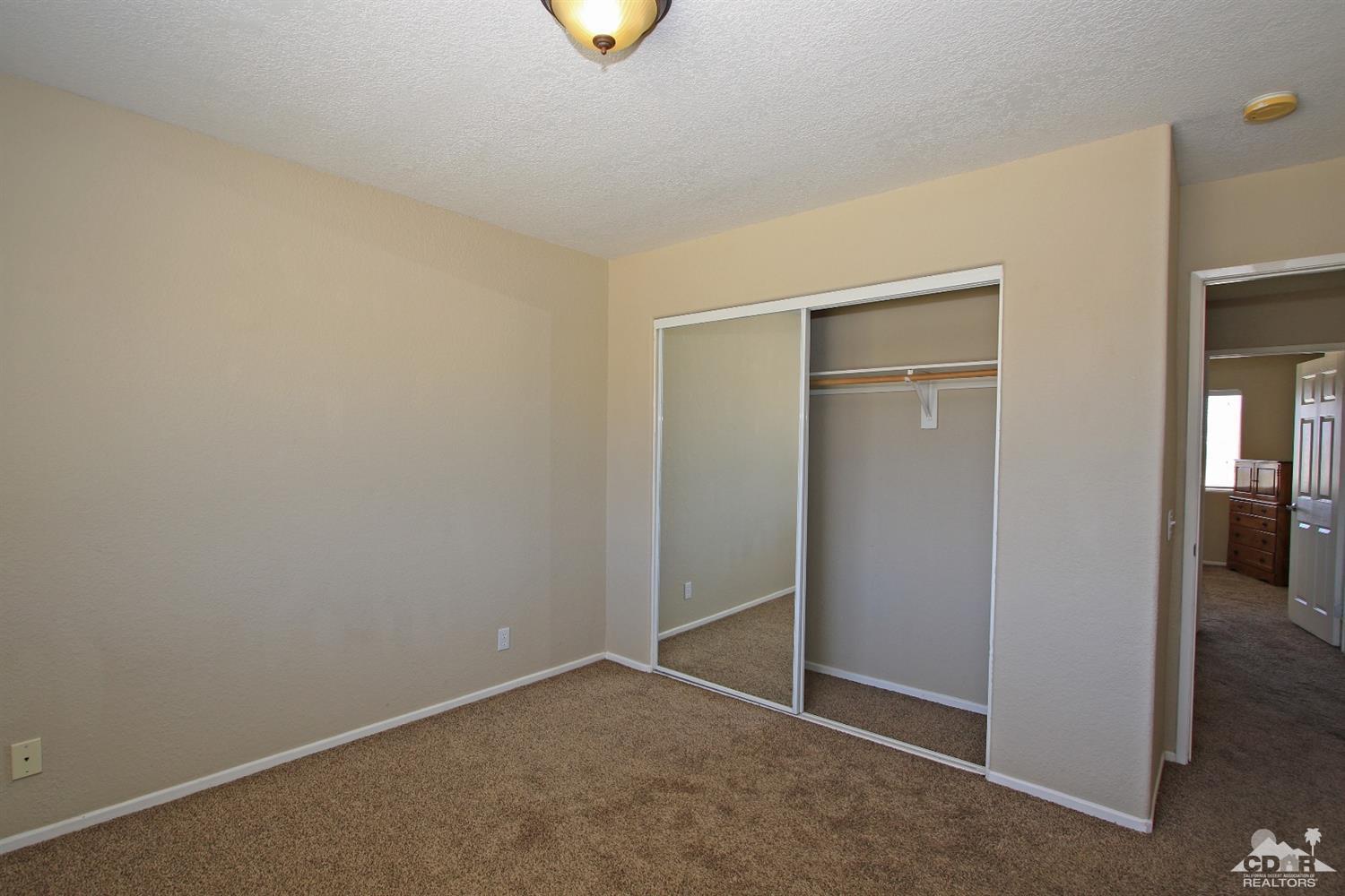 13810 United Road Desert Hot Springs, CA 92240 - Photo 23 of 41 an empty room with closet and mirror