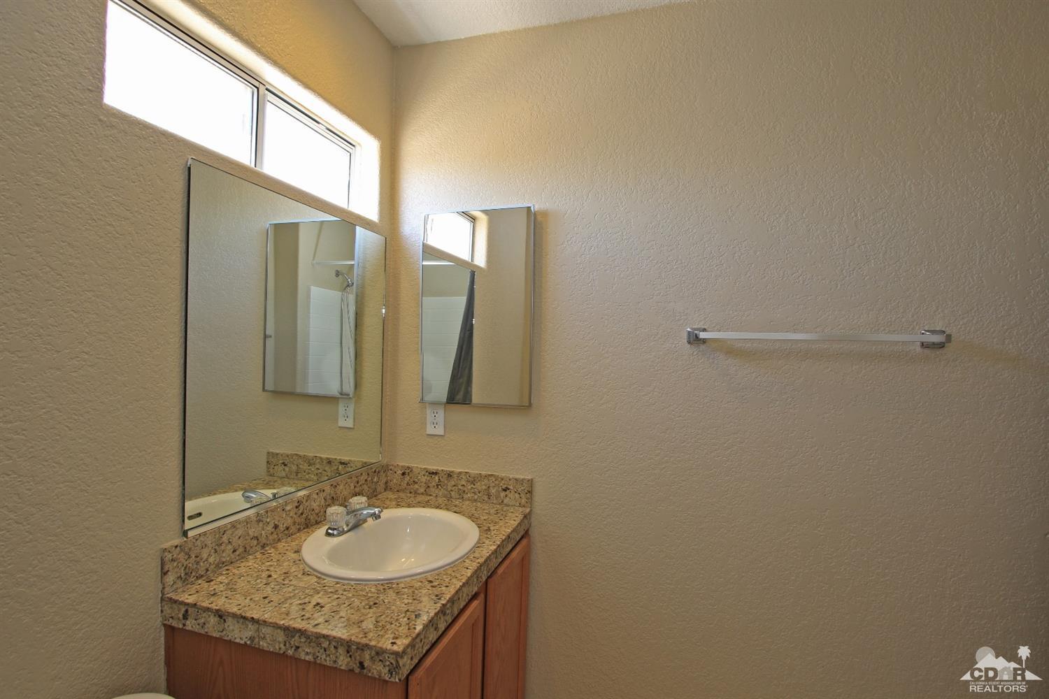 13810 United Road Desert Hot Springs, CA 92240 - Photo 27 of 41 a bathroom with a granite countertop sink and a mirror
