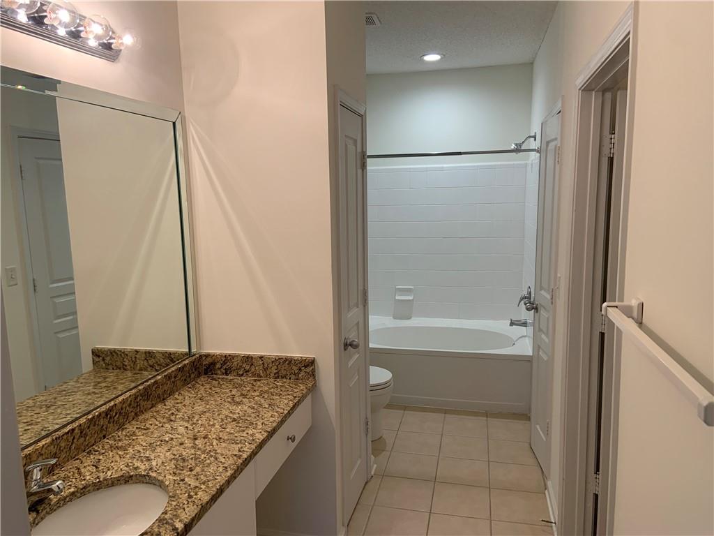 10 Perimeter Summit Boulevard, Unit 1404 Brookhaven, GA 30319 - Photo 15 of 39 a bathroom with a granite countertop sink a toilet and shower