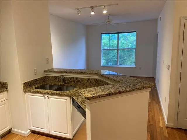 a view of kitchen island a sink wooden floor and a window