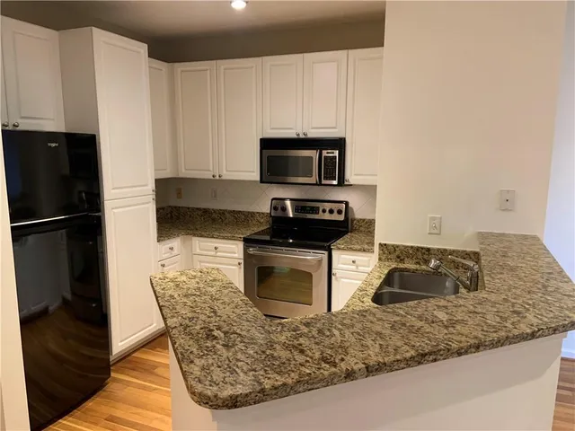 a kitchen with a sink a microwave a refrigerator and cabinets