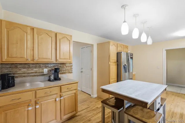 a kitchen with stainless steel appliances granite countertop a kitchen island a stove a refrigerator a sink dishwasher a dining table and chairs with wooden floor