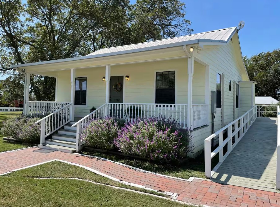 1281 Post Oak Point Road New Ulm, TX 78950 - Photo 6 of 29 A charming, accessible home features a welcoming front porch, a practical ramp entry, and vibrant landscaping.
