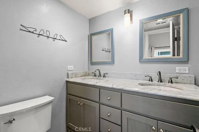 a bathroom with a granite countertop toilet sink and mirror