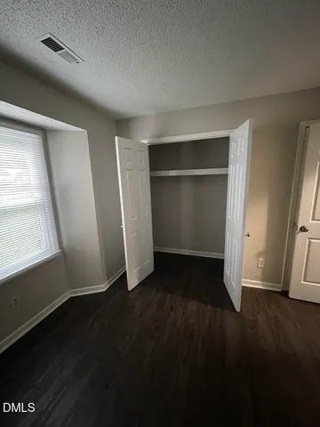 an empty room with wooden floor closet and windows
