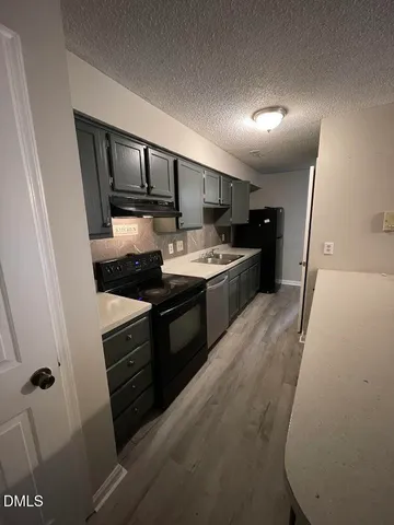 a kitchen with granite countertop a sink stove and refrigerator