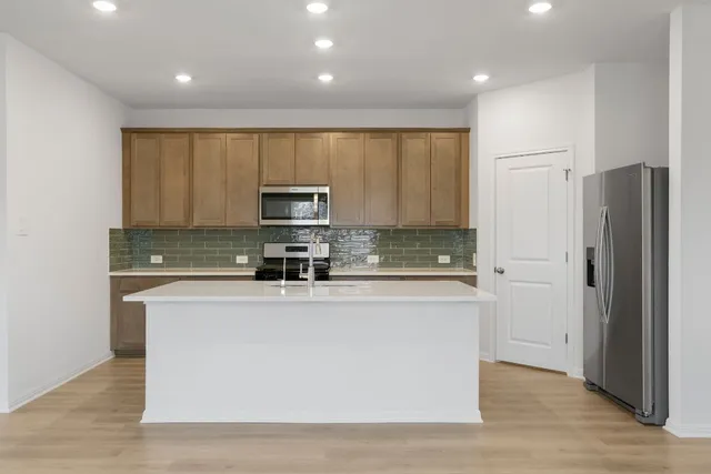 a kitchen with stainless steel appliances a sink a stove a microwave a sink and cabinets