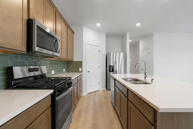 a kitchen with stainless steel appliances granite countertop a refrigerator stove microwave and sink