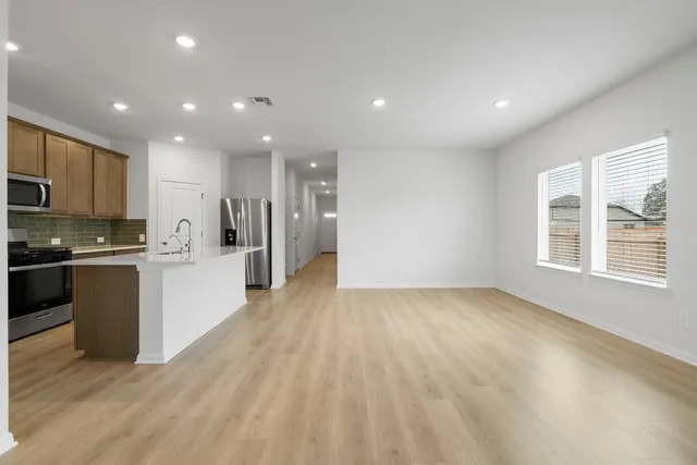 a view of kitchen with kitchen island granite countertop a stove top oven a sink and a counter top space
