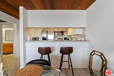 a kitchen with stainless steel appliances granite countertop a sink a stove a dining table and chairs