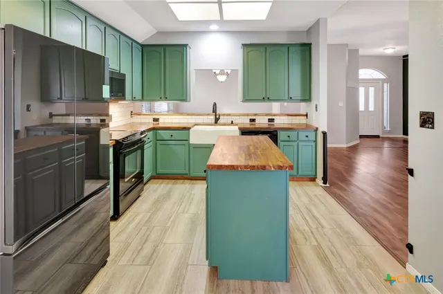 a large kitchen with kitchen island a sink stainless steel appliances wooden floor and cabinets
