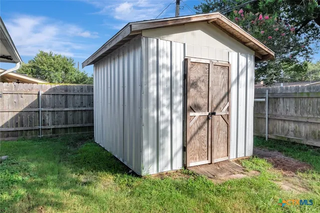 a backyard of a house with plants and wooden fence